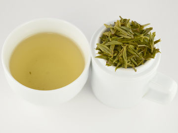 曲げられた形の新しい茶葉が付いている袋に入れられた有機性緑茶のドラゴンの井戸の茶